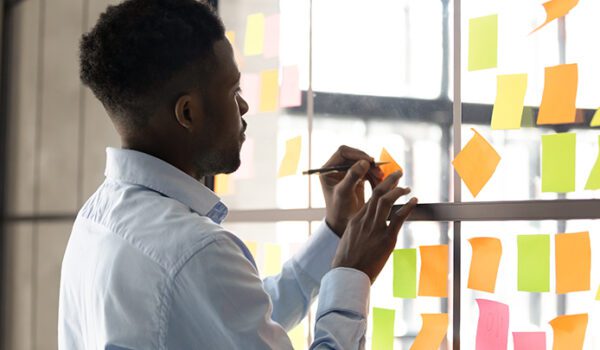 Young man writes on sticky notes, planning digital PR campaign