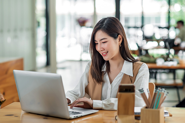 Happy young businesswoman sitting at table in cafe with tabletop computer.