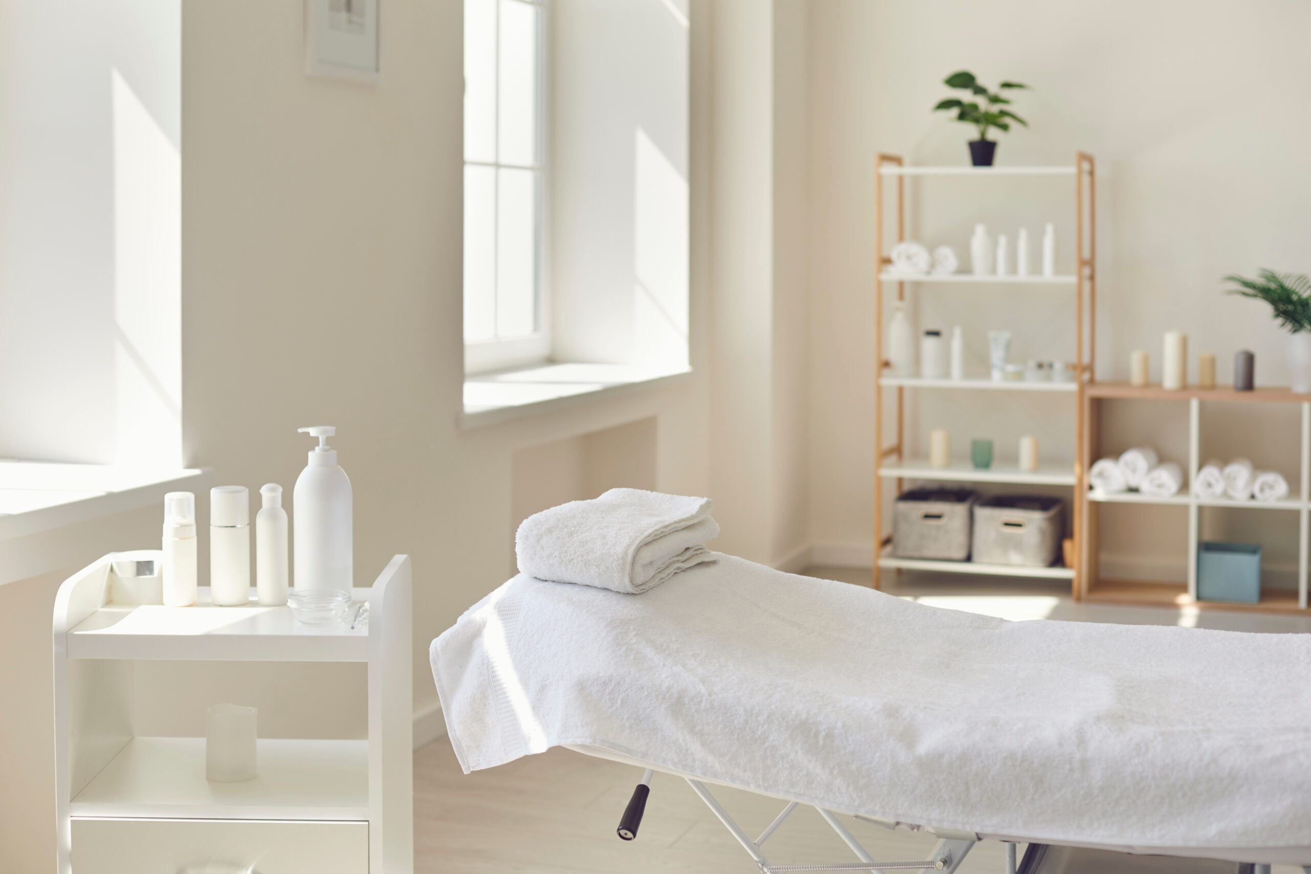 Interior of beauty salon with spa massage table and set of skincare products ready for use