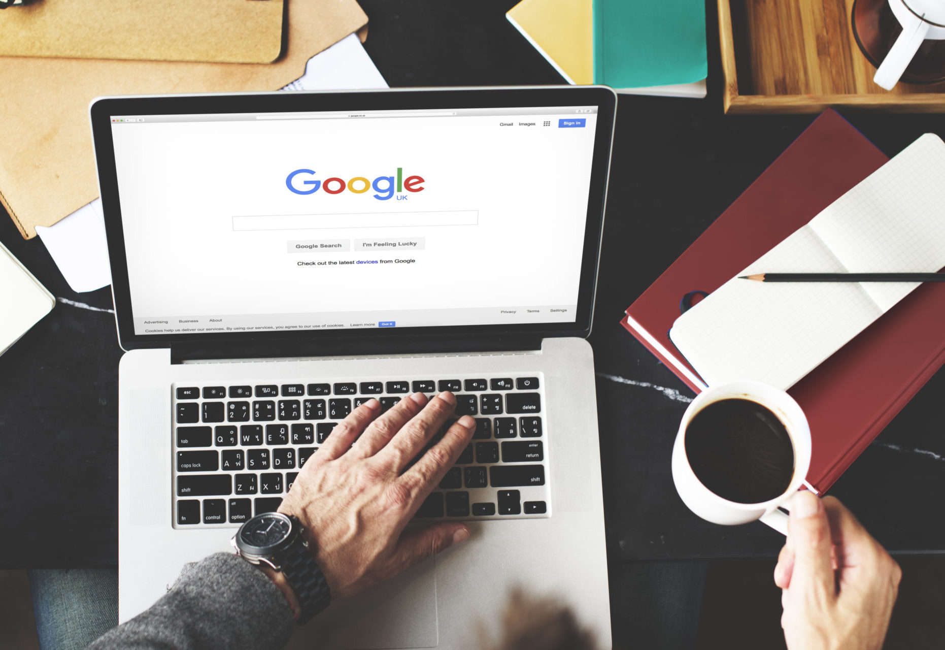 person browsing google on macbook while holding coffee mug