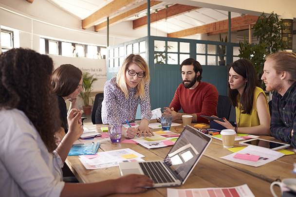 Woman Showing Team Papers At Table Meeting